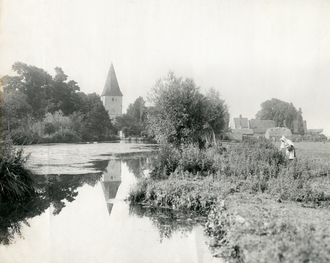 Photograph of view at Bosham, church in background, water in foreground, 1896